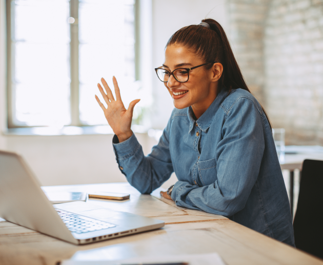 Woman waving at computer while on a video call